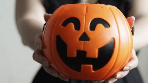 Happy Halloween,pumpkin candy bowl with lollipops hold by a woman in a witch costume,holiday evening of all saints,backdrop for scary ghosts and fun sweet treats – Video có sẵn