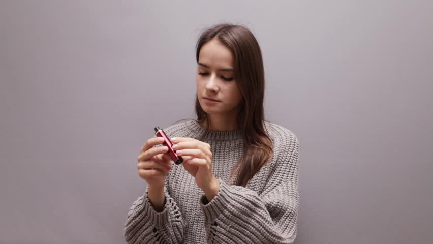 teenager girl looks at a disposable cigarette, stop vape smoking, tobacco addiction of minors, choice of young people, nicotine refusal