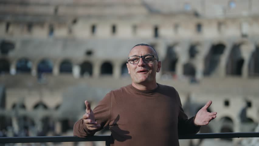 Happy surprised man rising hands showing gesture at sightseeing of Colosseum in Rome, slow motion cinematic isolated shot with selective focus