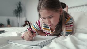Elementary age girl studying while lying on front on the bed. Shot with RED helium camera in 8K. 