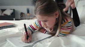 Elementary age girl studying while lying on front on the bed. Shot with RED helium camera in 8K. 