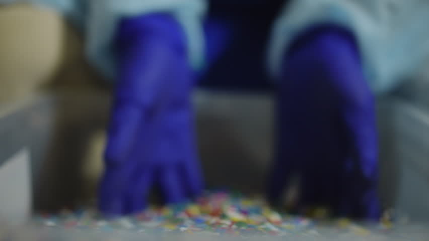 Close-up shredded multicolored plastic garbage with female hands in gloves raising smashed trash showing colorful parts falling in box. Recycling and waste separation concept Royalty-Free Stock Footage #1107931979