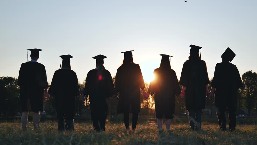 College graduates in robes waving at sunset. | Shutterstock HD Video #1107938749