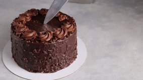 In the video, a knife smoothly slices a rich chocolate cake, revealing mousse and nut layers. The sumptuous piece, magnified for effect, teases the senses