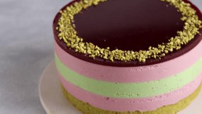 The video unveils an artisan mousse cake with pistachio and cherry layers, pistachio sponge, and cherry jelly, all shining in natural hues