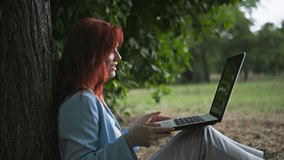 outdoor office, beautiful young woman working remotely talking on video call with clint sitting near tree in park