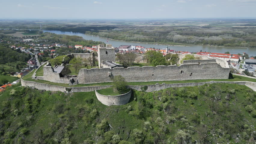 Aerial around view of ruined castle on hill, city Hainburg an der Donau and Danube river in Austria, 4k