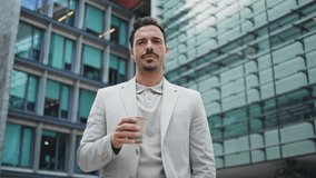 Business man sipping tea looking camera at city portrait. Successful young businessman face posing on glass walls architecture background close up. Elegant confident leader enjoying coffee at street - Powered by Shutterstock - Get 15% off with code: PIKWIZARD15