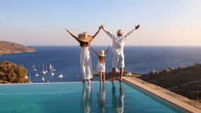 A happy family on summer holidays stands by the swimming pool and enjoys the beautiful sunset behind the mediterranean sea in Greece - Powered by Shutterstock - Get 15% off with code: PIKWIZARD15
