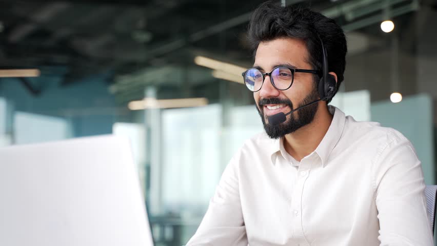 Close up. Corporate operator who works in customer support speaks on a video call using a laptop. Call center agent in wireless headset helping customer with complaints in office. Online consultation Royalty-Free Stock Footage #1107954683