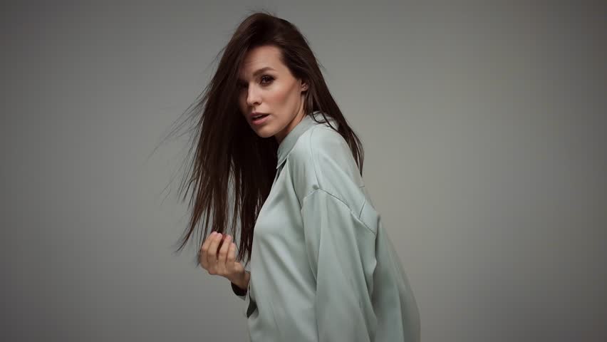 Beautiful brown-haired girl with a perfectly curly flying hair, classic make-up and a blue suit. Beauty face and hair.