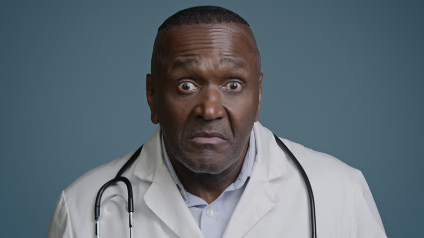 Close-up unsure confused ethnic african american man doctor surgeon in medical white coat in blue background studio shrug shake head making I don't know gesture no answer waving negative disapproval