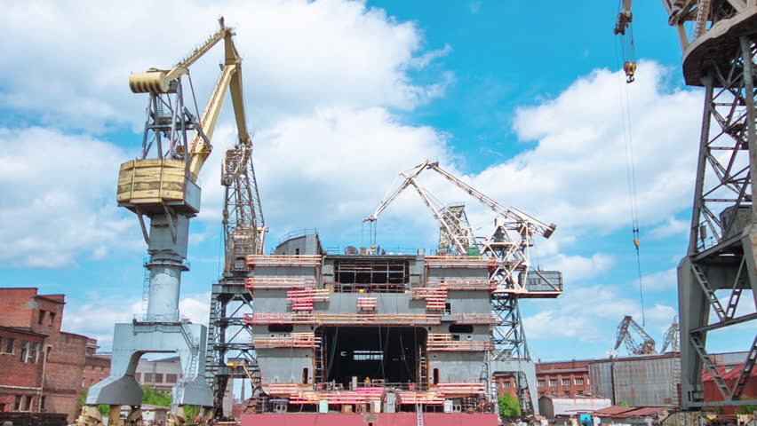 The construction of a large ship on a shipyard with cranes timelapse. A fragment of the case in the workshop of the plant. Metal frame during assembly front view. Cloudy sky Royalty-Free Stock Footage #1107957665