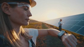 Female engineer smart watch chacking solar panels line status, looking at smartwatch. Male worker explore productivity of renewable resource with digital tablet. Green energy visualization. - Powered by Shutterstock - Get 15% off with code: PIKWIZARD15