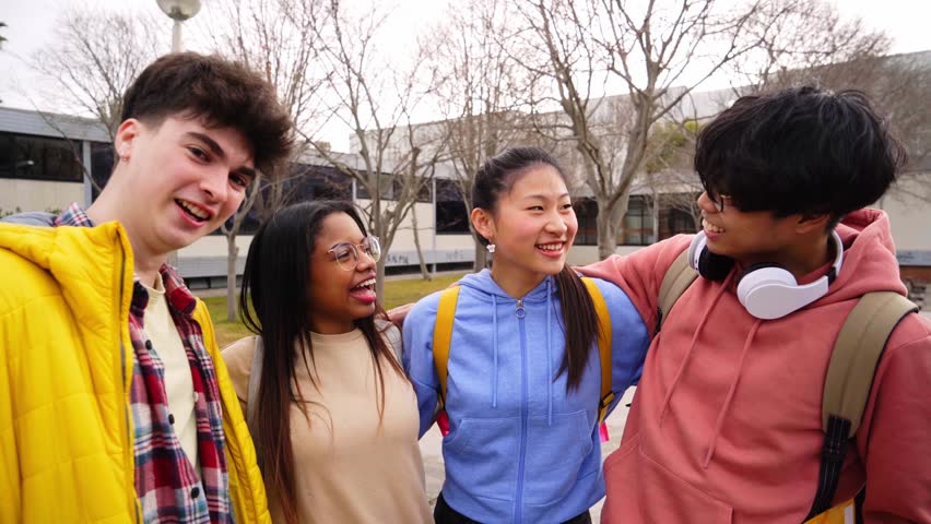 Confident multiracial group of students holding books and smiling at camera, campus university on background, learning and education concept. Smiling happy people having fun together. International