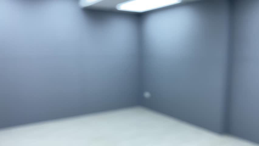 Blurred first person point of view walking in modern interior showroom with empty office space grey wall and white floor with light from ceiling feeling dizzy blurry and falling to the ground Royalty-Free Stock Footage #1107965241