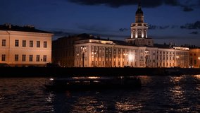 Group of tourist motor boats sails on Neva river in a summer night in Saint Petersburg city, Russia. Orange colored building illumination. Real time handheld video. Water transport theme