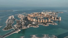 The drone is flying high looking at the Pearl neighbourhood on a sunny day in Doha Qatar Aerial Footage 4K