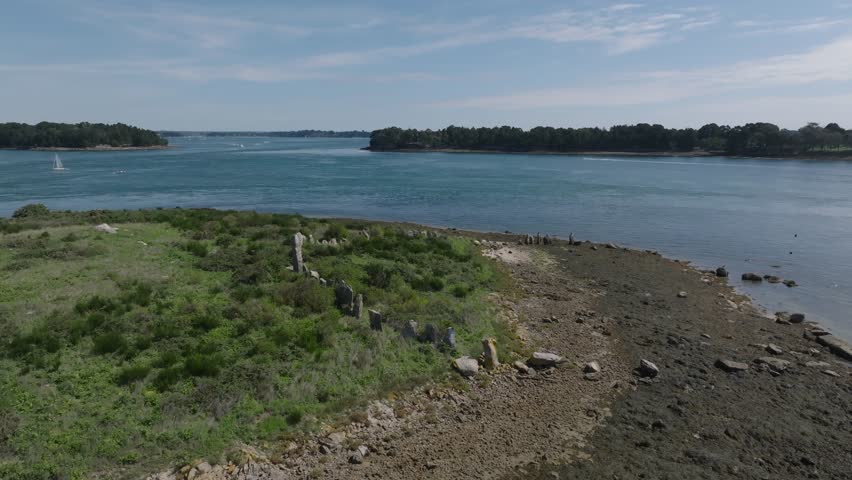 Drone shot of the cromlech of Er Lannic. It is a double megalithic enclosure located on  the islet of Er Lannic in Arzon, in the French department of Morbihan in the Brittany region. Royalty-Free Stock Footage #1107970951