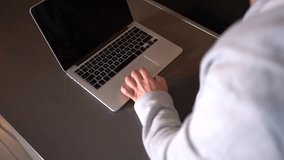 Hands of a young man teleworking from home in the kitchen conducting a work meeting on video call with laptop, 4k video