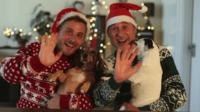 gay male couple greet camera at christmas with christmas hat and puppieslgbt family video call - Powered by Shutterstock - Get 15% off with code: PIKWIZARD15