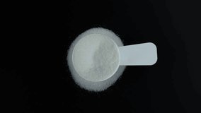 Disodium monohydrogen citrate in measuring scoop, top view. Pile of Sodium citrate powder. Food additive E331 uses in food industry. 4K video, Rotating.