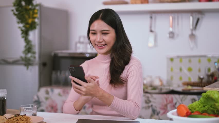 Beautiful Asian woman using an application to send a instant message in her smartphone device while eating spaghetti