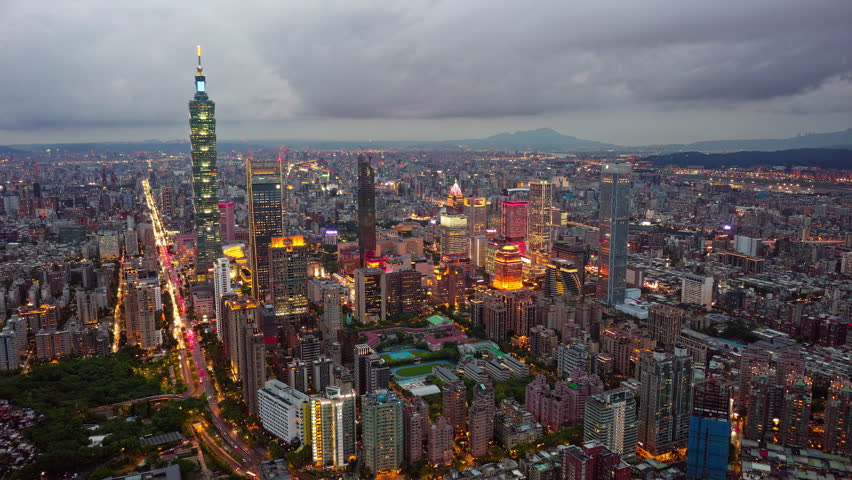 Aerial hyperlapse at sunset above Downtown Taipei, the vibrant capital of Taiwan, with 101 Tower standing out amid skyscrapers in XinYi Commercial District and city lights dazzling under twilight sky Royalty-Free Stock Footage #1107987561
