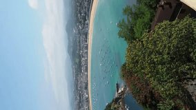 Aerial view of La Concha Bay in San Sebastian city during summer with boats on the shore and the beach. Vertical panoramic video with copy space of beach city with turquoise water. 
