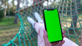 A green screen on a smartphone in the hands of a woman. The girl rests in a forest camp in nature. - Powered by Shutterstock - Get 15% off with code: PIKWIZARD15