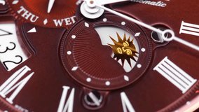Extreme closeup of  second arrow passing by on clock face. Lengthwise view of luxury swiss watch. Running second arrow. day and night indicator on the watch face. burgundy watch face