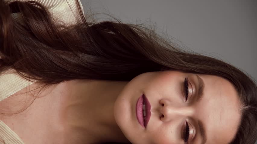 Beautiful brown-haired girl with a perfectly flying hair, classic make-up and a light dress. Beauty face and hair.