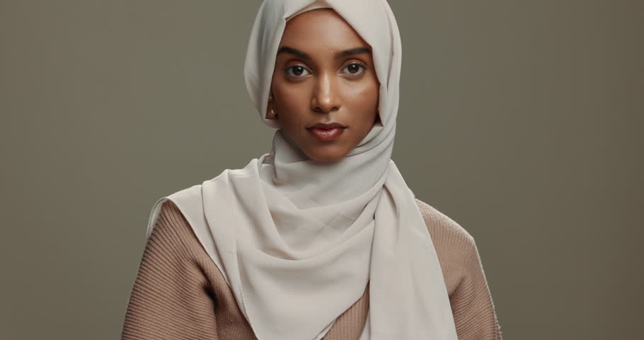 Fashion, face and a Muslim woman with a hijab on a studio background for classy and elegant style. Serious, beautiful and portrait of an Islamic model or girl with a headscarf isolated on a backdrop Royalty-Free Stock Footage #1108000099