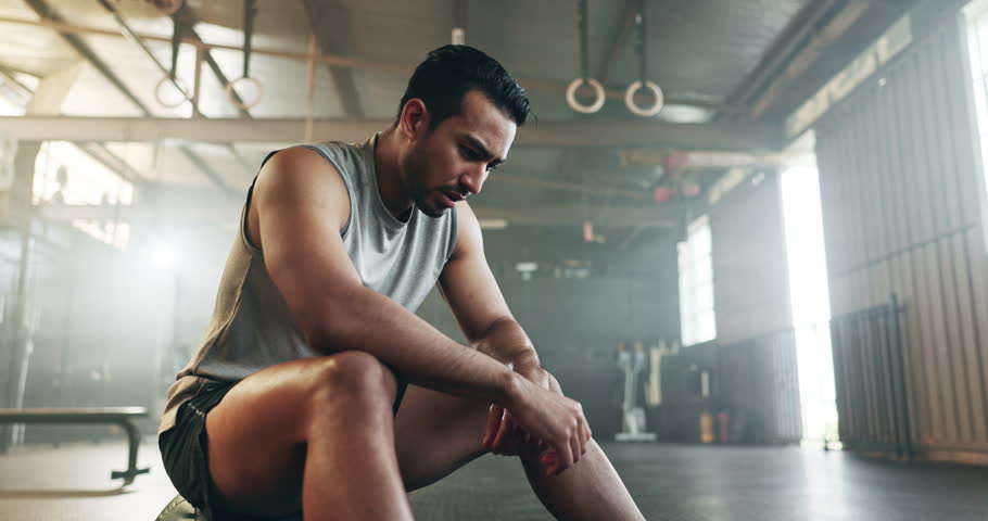 Fitness, breathing and sweating with a tired man in the gym, resting after an intense workout. Exercise, health and fatigue with a young athlete in recovery from training for sports or wellness
