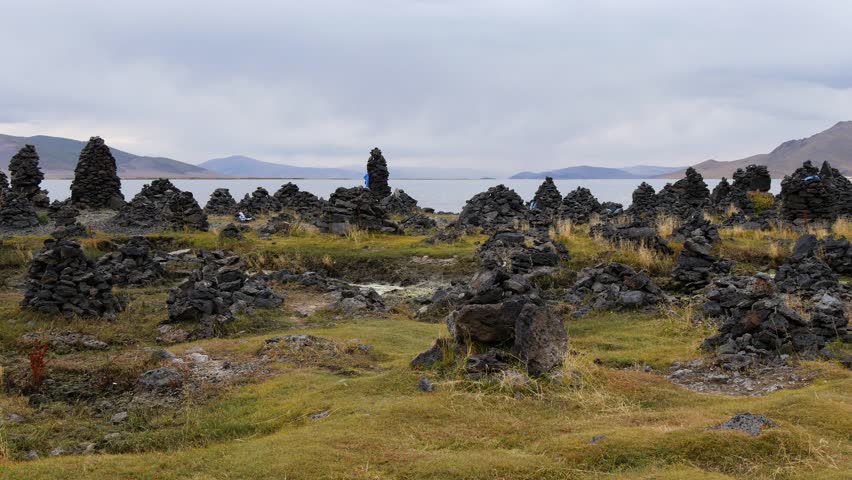 Man-made stone pillars made of volcanic stones on the shore of Tsagan Nuur Lake in autumn evening, Mongolia. | Shutterstock HD Video #1108003657