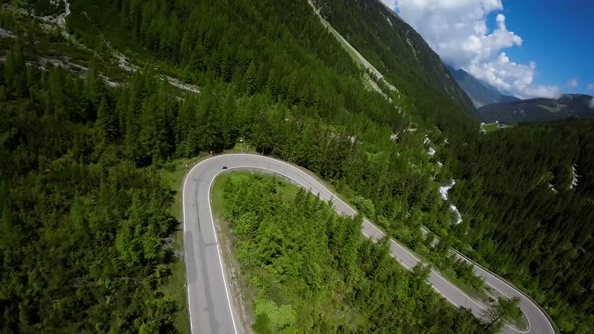 motorcycle rider ride in perfect along a scenic mountain mountain road in austria. As a DJI FPV drone captures spectacular aerial footage. Royalty-Free Stock Footage #1108004177