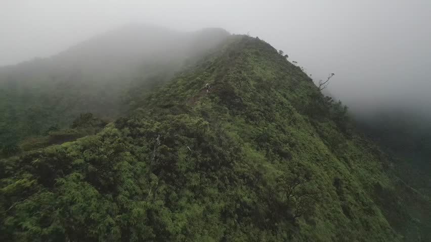 Aerial: Two women hike up foggy ridge trail on Stairway to Heaven