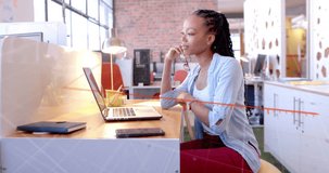 Animation of diagram over biracial businesswoman using laptop in office. Global business, technology and digital interface concept digitally generated video.