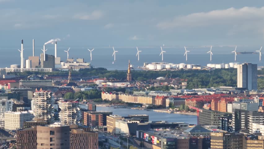 Scenic aerial of wind turbines, seaside industrial zone and commercial buildings in Copenhagen, Denmark.