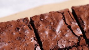 Close-up video of freshly baked brownie cubes, highlighting their crumbly crust and rich interior. The focus is on texture and the irresistible allure of this classic treat