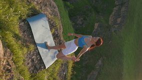 Vertical Video, Athletic Woman Doing Yoga Poses on Top Mountain During Sunset. Sports Girl Trains and Does Stretching Exercises in Mountains. Healthy Lifestyle, Zenism, Workout Concept. Slow Motion