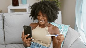 African american woman holding pregnancy test having video call at home