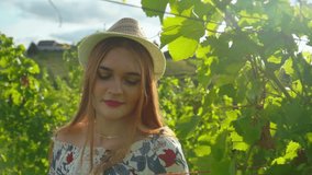 Stunning HD footage of a young white Caucasian woman gently touching the green leaves with her hand in a vineyard in the heart of Prlekija, Slovenia. Video captured during a sunny summer day.