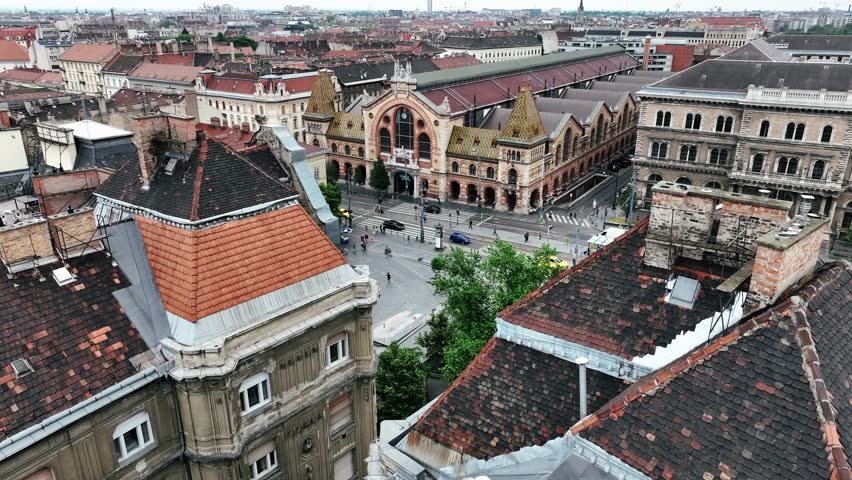The drone is flying towards the Great Market Hall flying just above the roofs of old buildings in Budapest Hungary Aerial Footage 4K