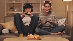 Young asian couple family playing online video games with neon  light living room at home.