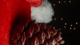 Vertical video. A pinecone rests on Santa's hat against the backdrop of a garland. Close-up view. - Powered by Shutterstock - Get 15% off with code: PIKWIZARD15