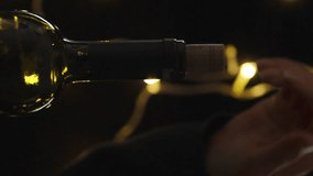 Vertical video. I pull out the cork from the wine bottle against the backdrop of the nighttime garland.
