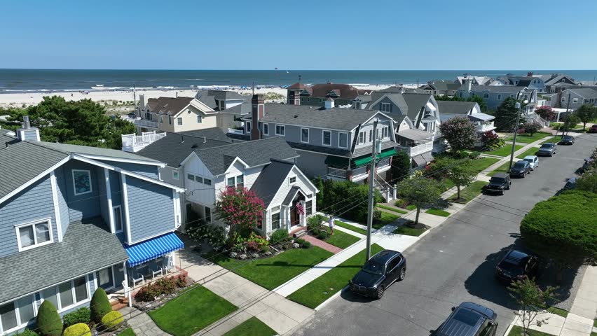 Beach houses with view of ocean. Aerial establishing shot of luxurious homes and rental properties at east coach beach on Atlantic Ocean. Beach town vibe with American flag.