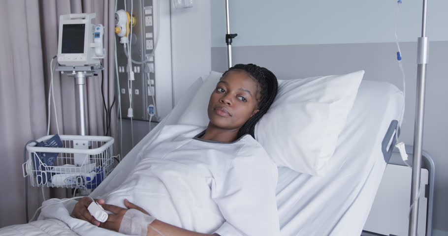 Happy african american female patient lying in bed in hospital room, slow motion. Medical services, healthcare and medicine, unaltered. Royalty-Free Stock Footage #1108032435