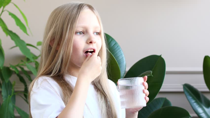 The girl takes vitamins and drinks them with water. Schoolgirl. Pills.